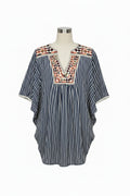 A women's short-sleeve top with vertical navy and white stripes, featuring a V-neckline with colorful geometric embroidery in red, orange, and green, and a cream-colored collar.